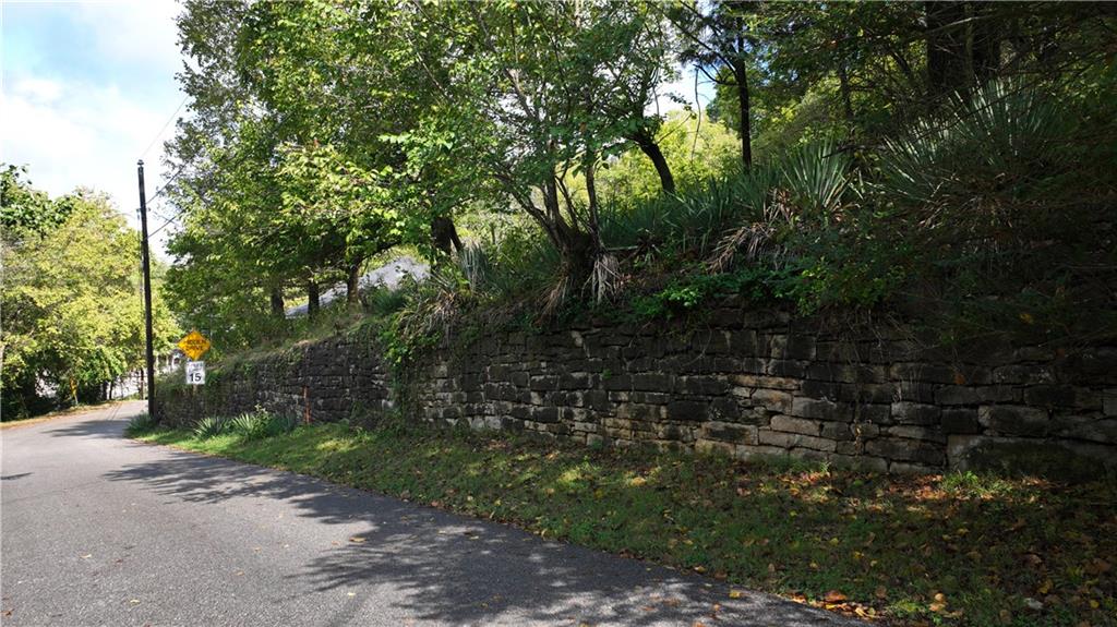 Street view of lot on hillside that begins with a stone retainer wall